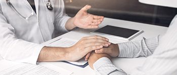 상담 중 환자의 손을 잡아 주는 의사